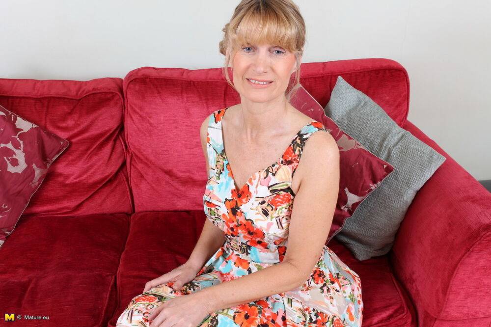 Mature woman takes off her dress and pretties to on a red sofa | Photo: 744149