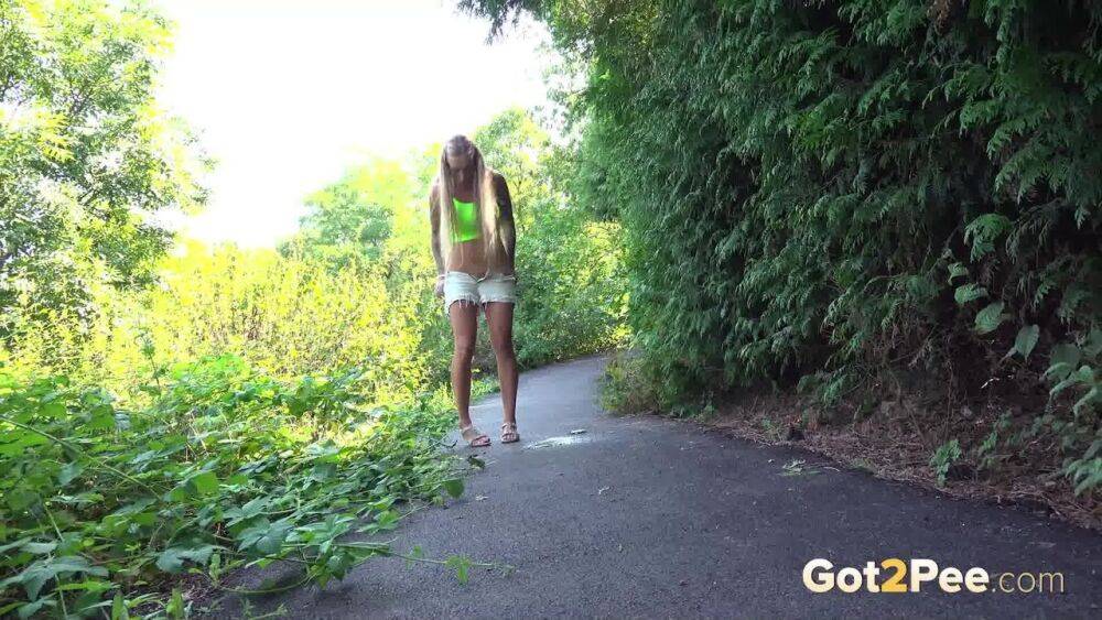 Blonde teen Daisy Lee takes a piss on a paved path through the woods - #1