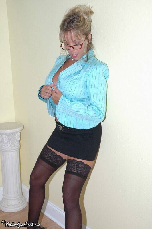 Older blonde Amber Lynn Bach looks over her glasses while disrobing in hosiery - #2