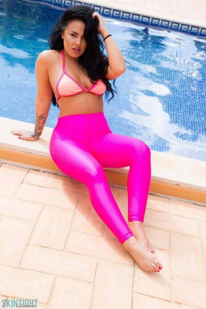 Glamour model Olivia Paige slips pink leggings over bikini bottoms by a pool - #6