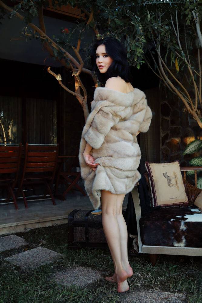 Beautiful dark haired teen removes a fur coat to model naked on a patio - #11