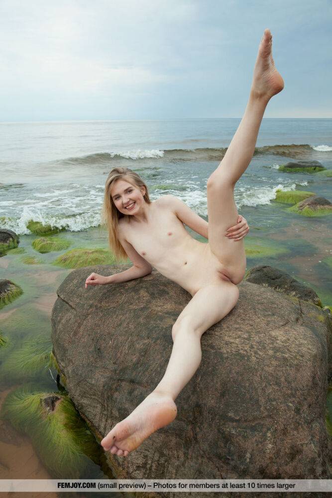 Slim teen Nimfa removes a black bikini to pose naked on seaside rocks - #10