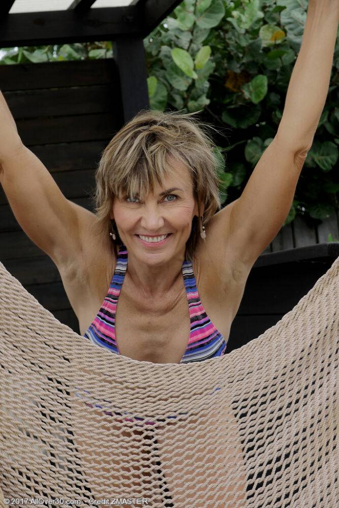 Mature woman Lillian Tesh fingers her pussy on a hammock after bikini removal - #9