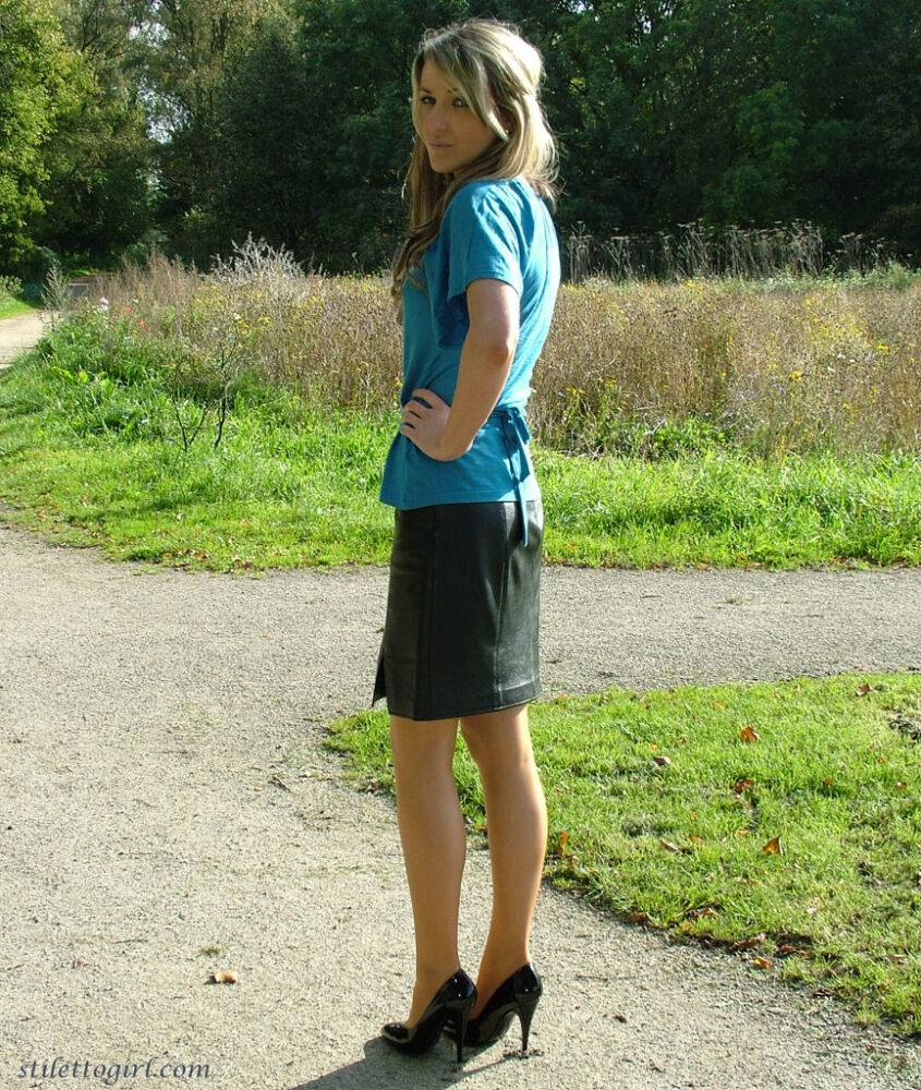 Clothed woman shows off her shapely legs outdoors in a skirt and black pumps - #3