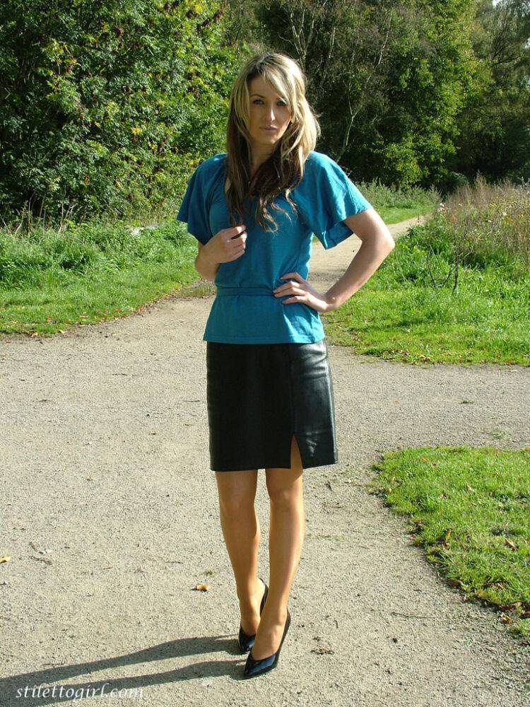 Clothed woman shows off her shapely legs outdoors in a skirt and black pumps - #8