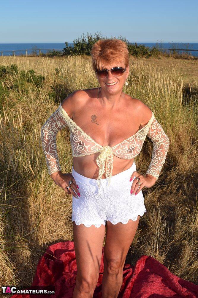 Fit older lady Dimonty exposes big naturals on a blanket overlooking the ocean - #16