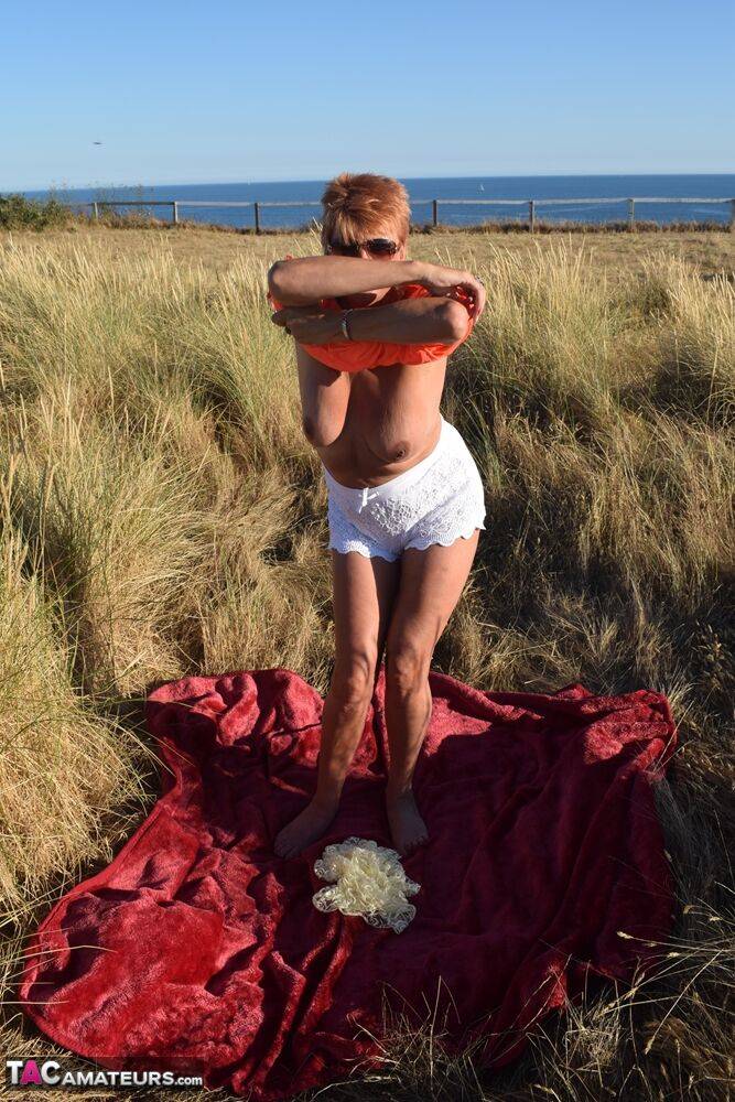 Fit older lady Dimonty exposes big naturals on a blanket overlooking the ocean - #5