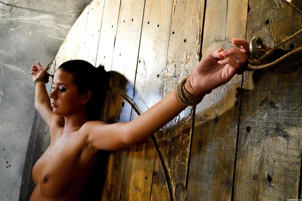 Mia Manatote is restrained to a wooden wall before painful nipple pegging | Photo: 2456806