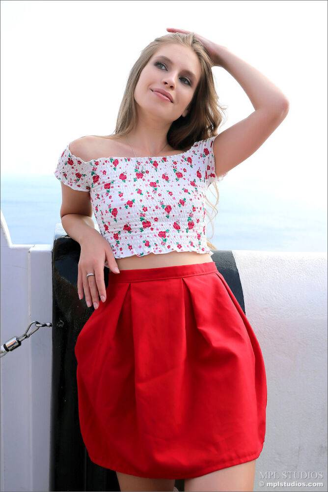 Pretty girl models fully clothed in a red skirt while on vacation | Photo: 2657252