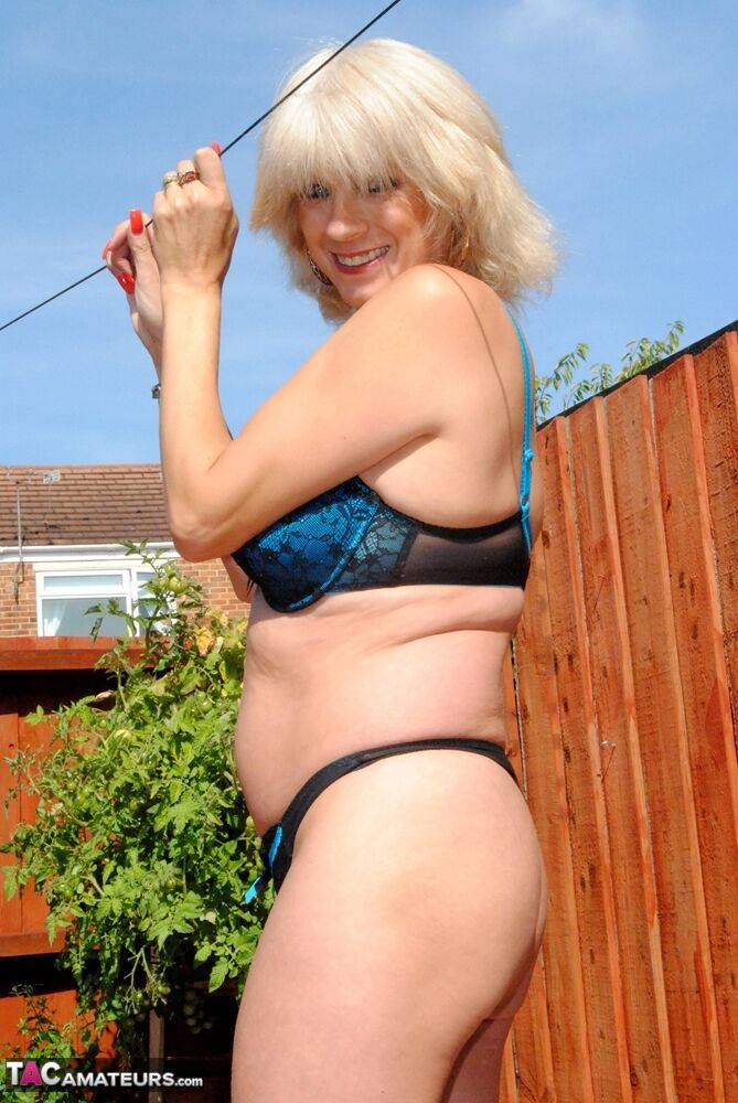 Mature blonde Dimonty models a bra and thong ensemble in a yard - #11