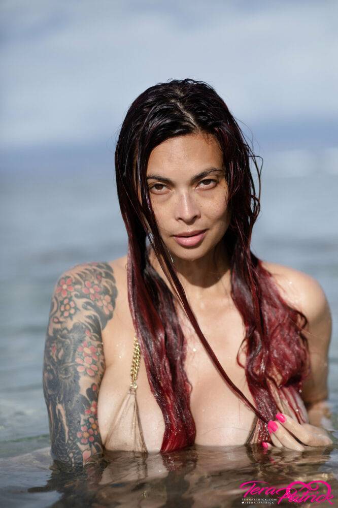 Asian chick Tera Patrick models in the ocean while wearing a gold bikini - #1