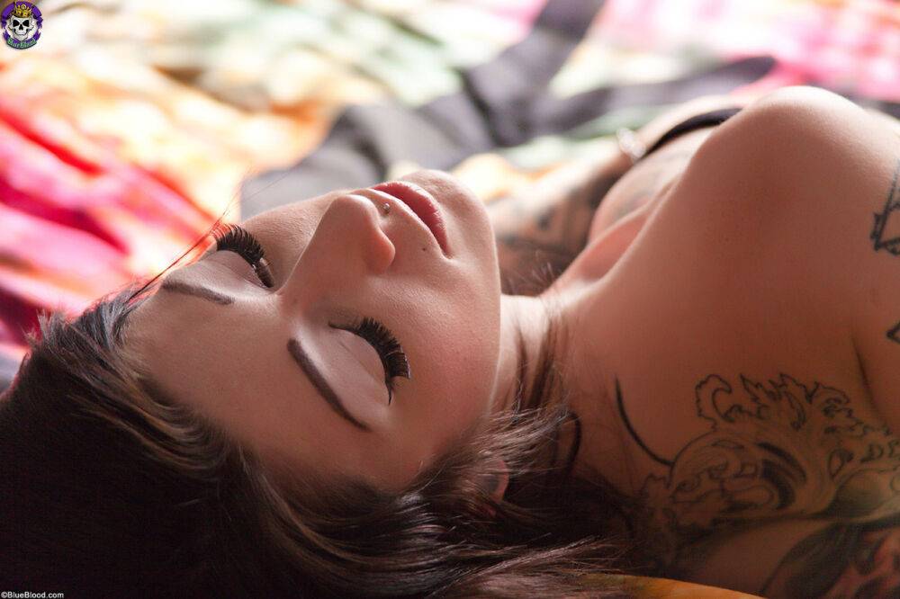 Tattooed silicone Angel Beau models naked on a bed in a garter and knee socks | Photo: 2711416