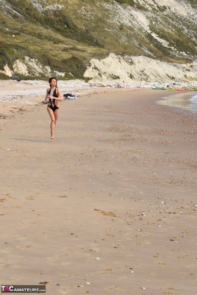 Slender female models a bathing suit while at a deserted beach - #6