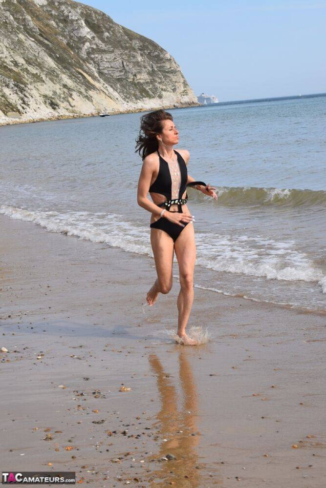 Slender female models a bathing suit while at a deserted beach - #3