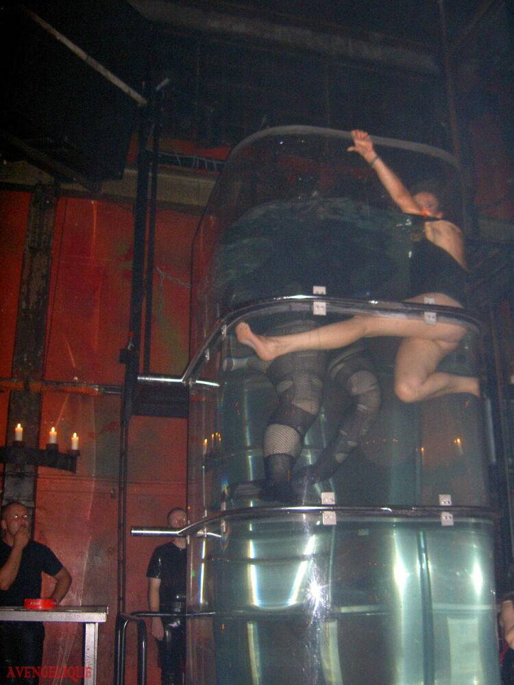 Caucasian female Dark Wing models latex apparel while in a watery cage - #15