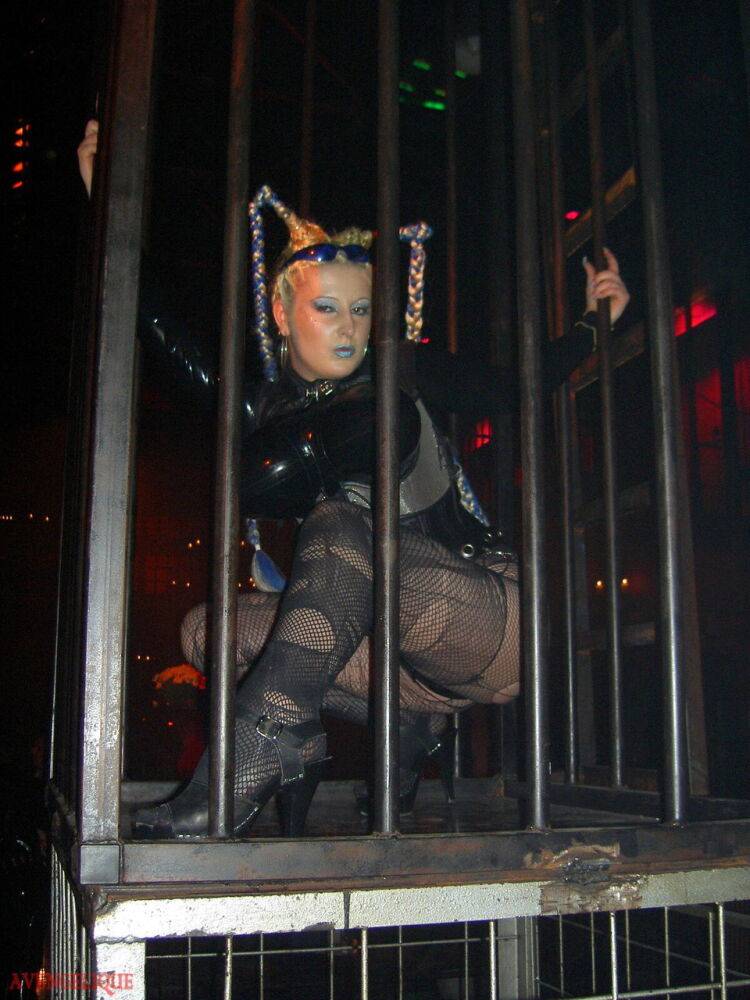 Caucasian female Dark Wing models latex apparel while in a watery cage - #5