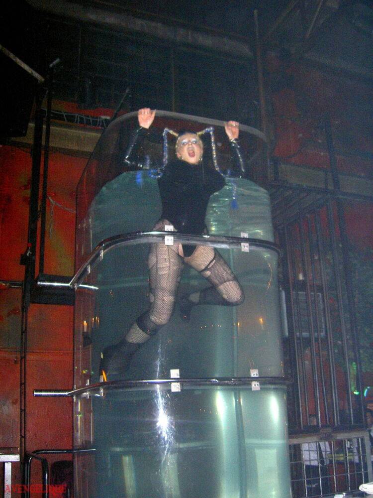 Caucasian female Dark Wing models latex apparel while in a watery cage - #11