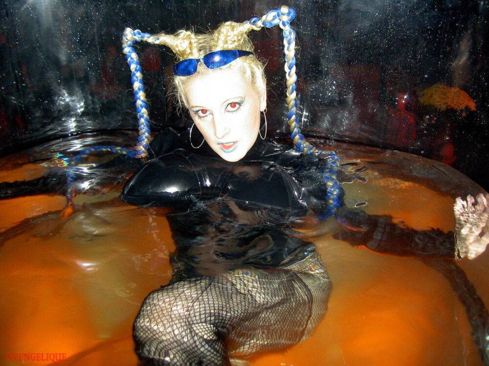 Caucasian female Dark Wing models latex apparel while in a watery cage - #4