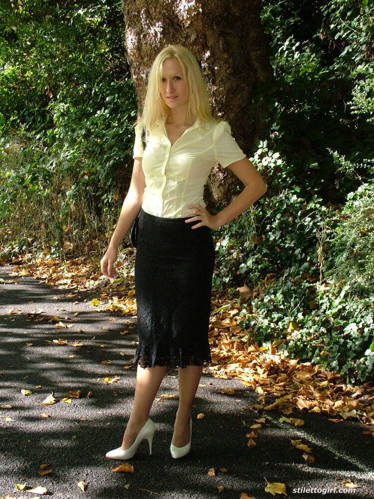 Clothed blonde Iona shows off her white stilettos in a long skirt by a park - #1