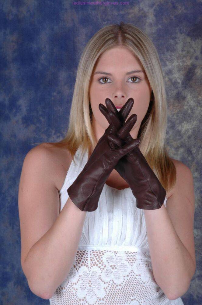 Blonde female pulls on brown leather gloves while wearing a white dress - #9