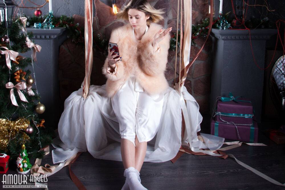 Young blonde Yulya gets naked near a Christmas tree in frilly white socks - #1