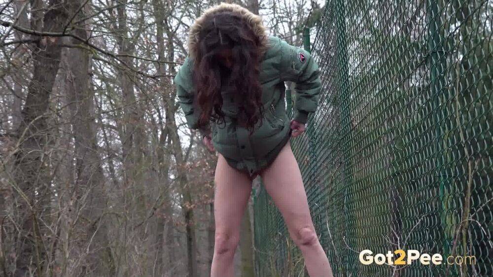 White girl Ali Bordeaux squats for a piss against a fence in a winter coat - #10