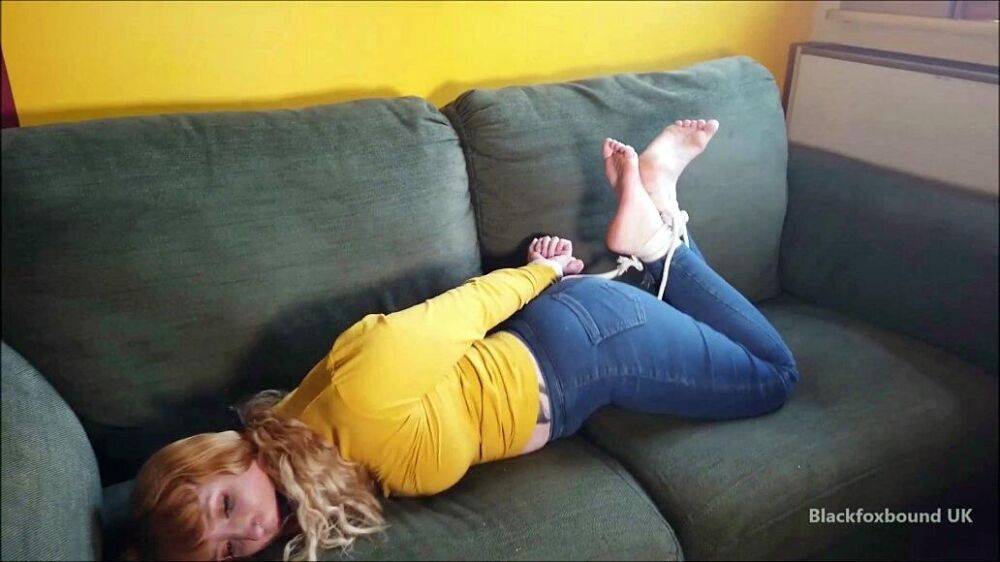 Barefoot white girl is hogtied on a sofa while ball gagged in her clothing - #16