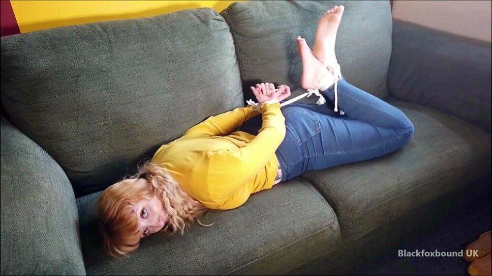 Barefoot white girl is hogtied on a sofa while ball gagged in her clothing - #4