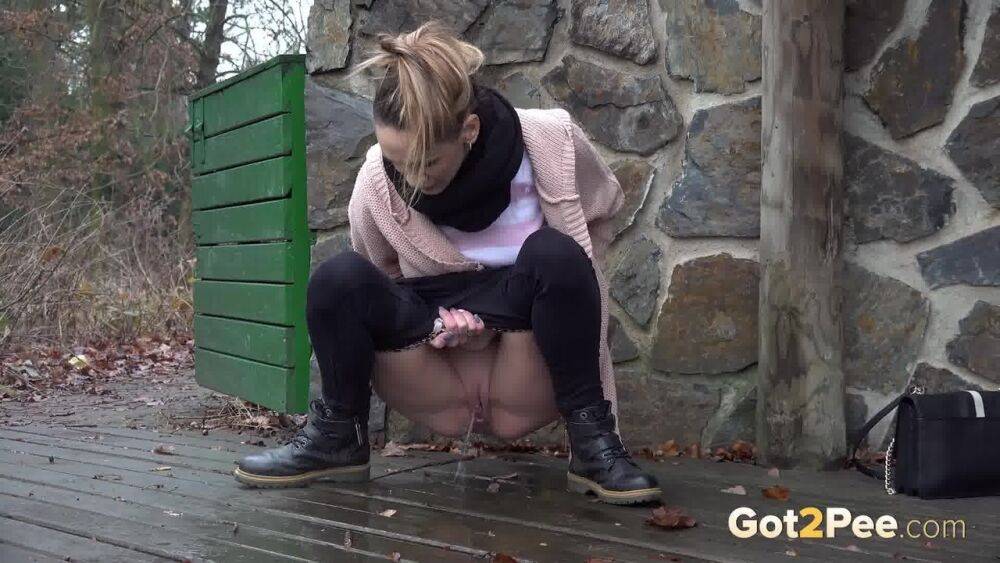 White girl Cynthia Vellons takes a piss on a deck behind a stone structure - #7