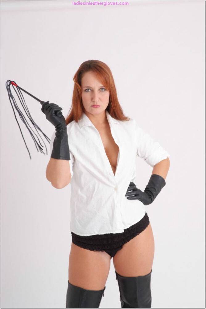 Pale redhead flexes a flogger while wearing black leather gloves and boots - #5