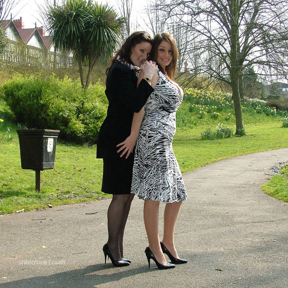 Clothed ladies hold hands while showing their spiked heels on a walking path - #15