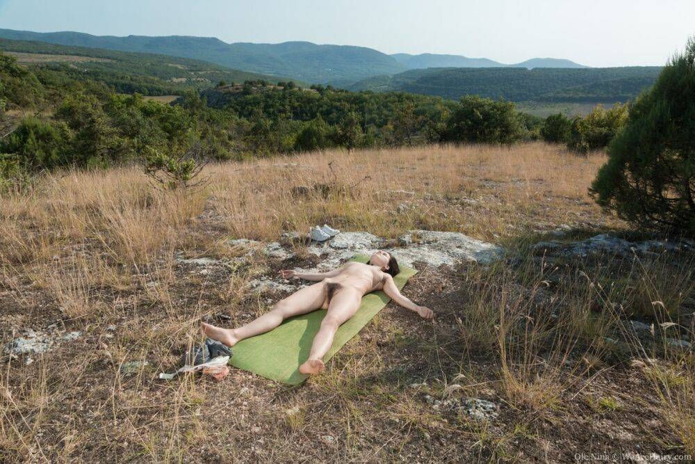 All natural amateur Ole Nina lays on a yoga mat under the clear sky atop hill - #8