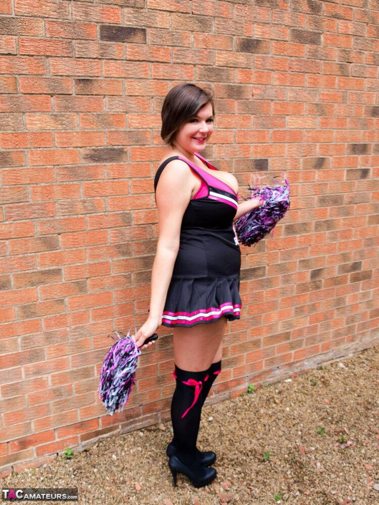 Chubby cheerleader Roxy uncovers her large tits against a brick wall - #9