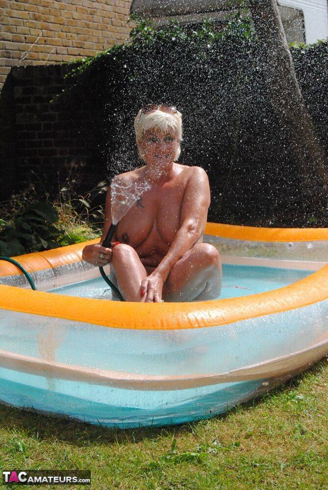 Mature blonde Dimonty takes off her wet T-shirt while in a wading pool - #13