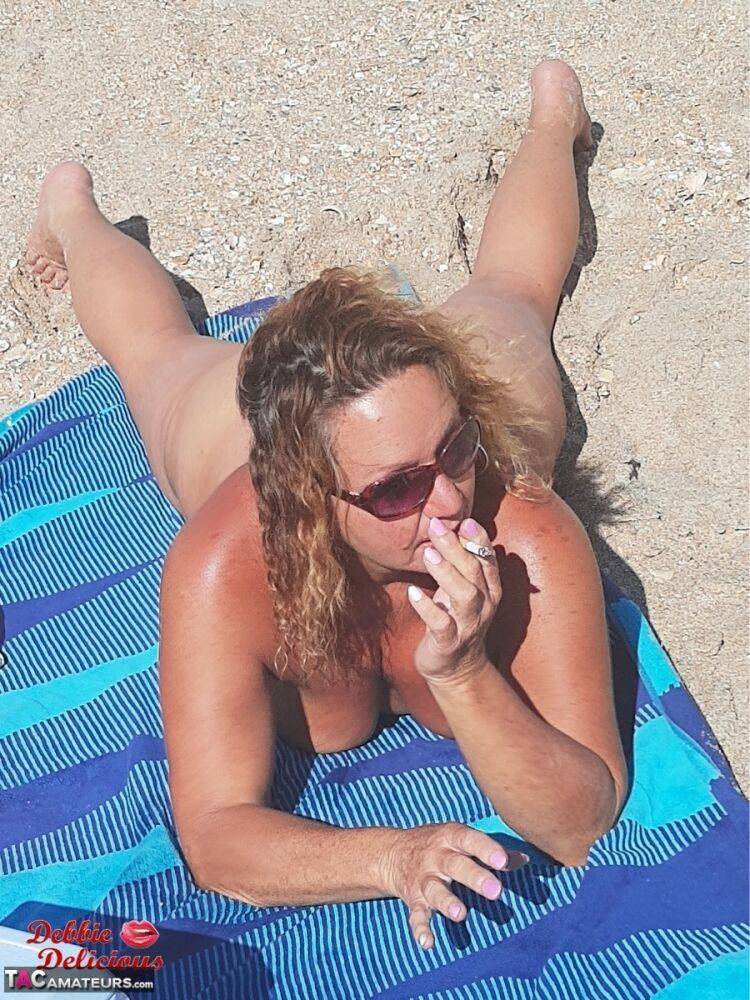 Older amateur Debbie Delicious smokes while sunbathing in the nude on a beach - #5