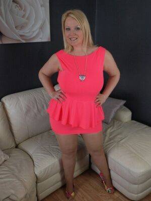 Thick amateur Sindy Bust teases on leather furniture in a short pink dress on picsofsex.com