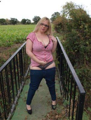 Amateur BBW Sindy Bust exposes her big boobs and twat on a countryside bridge on picsofsex.com