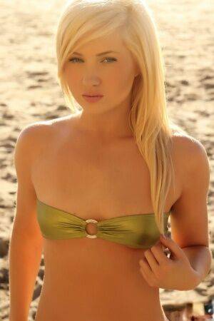 Young looking blonde girl Ashlie Madison cups her flat chest via bikini top on picsofsex.com