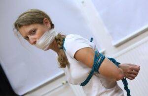 Clothed woman sports a pigtail while being gagged and tied up with rope on picsofsex.com