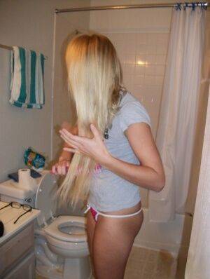 Blonde amateur Elle brushes her hair in glasses and thong while in a bathroom on picsofsex.com