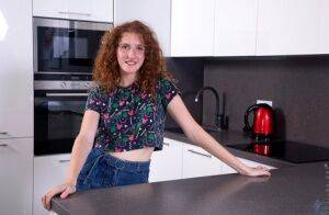 Teen solo girl Foxy Lee sports curly red hair while getting naked in a kitchen on picsofsex.com