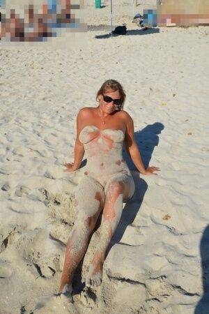 Naked amateur Sweet Susi covers her body in beach sand in sunglasses on picsofsex.com