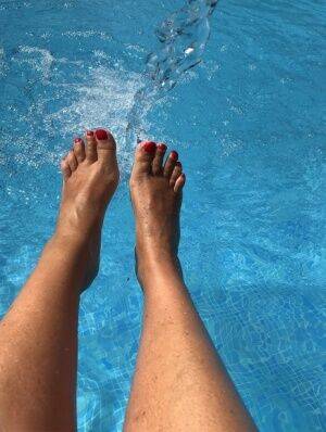 Mature woman Sweet Susi dips her painted toenails into a swimming pool on picsofsex.com