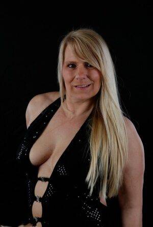 Older blonde Sweet Susi displays her inviting cleavage in a long gown on picsofsex.com