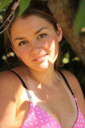 Petite amateur Allie Haze shows her tan lined body in the shade of a tree on picsofsex.com