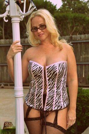 Blonde BBW Dee Siren shows her big ass in a hosiery and a corset while outside on picsofsex.com