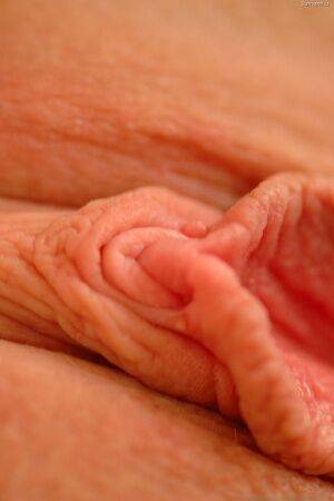 Erotic model stretches wide open to give a view of her bald pink pussy on picsofsex.com