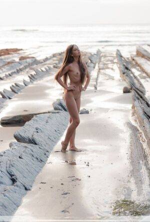 Slim girl Lorena G models totally naked on a seaside rock formation on picsofsex.com