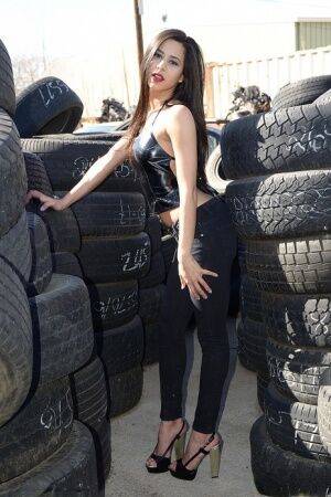 Latina amateur Bella Quinn covers her naked tits with hands amid tire stacks on picsofsex.com