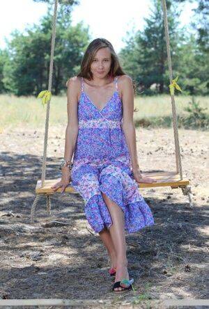 Long legged teen Mirabella doffs a dress to pose nude on a swing under a tree on picsofsex.com